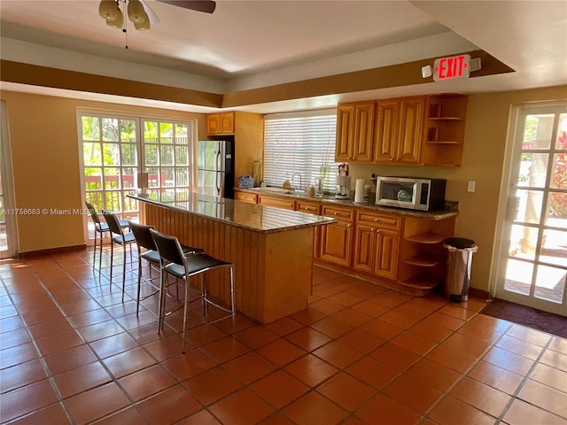 kitchen featuring stainless steel appliances, a kitchen island, a sink, and open shelves