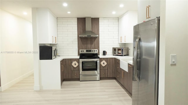 kitchen with appliances with stainless steel finishes, light countertops, decorative backsplash, and wall chimney exhaust hood