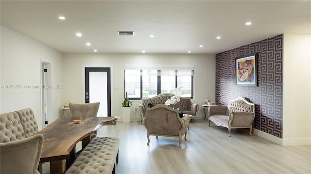 living room featuring an accent wall, recessed lighting, visible vents, and wallpapered walls