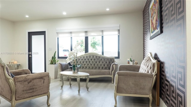 living area with an accent wall, recessed lighting, wallpapered walls, and wood finished floors