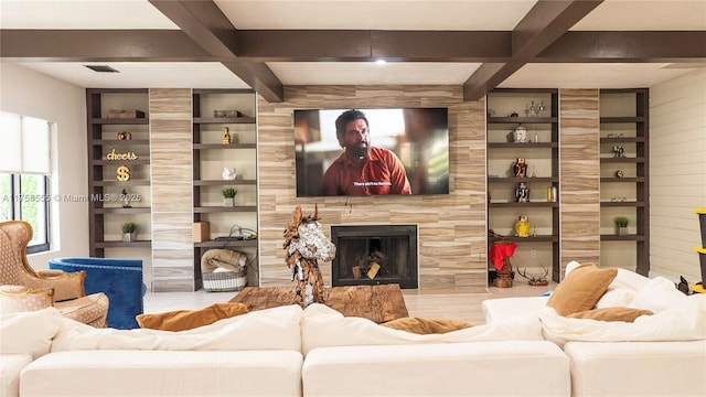 living area featuring built in shelves, a premium fireplace, coffered ceiling, and beam ceiling