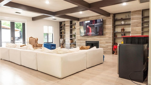 living room featuring built in features, a fireplace, visible vents, light wood-style floors, and beamed ceiling