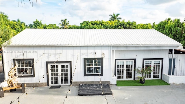 back of property with metal roof, french doors, board and batten siding, and a patio