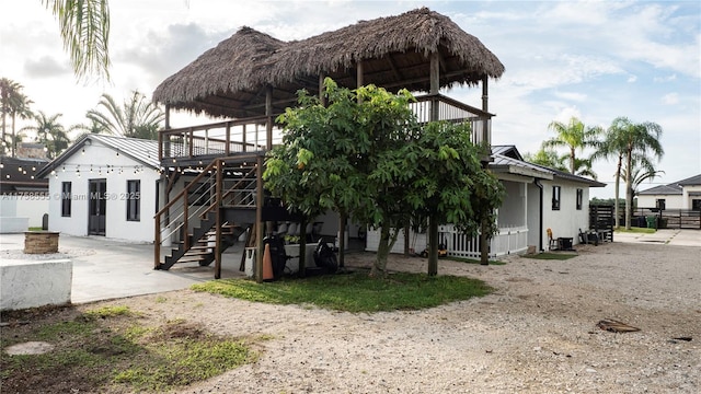 back of property featuring stairway, a standing seam roof, a patio area, metal roof, and fence