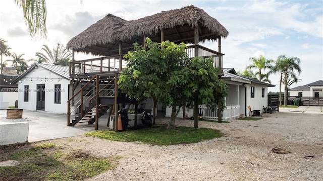 back of house featuring a standing seam roof, a patio area, metal roof, and stairs