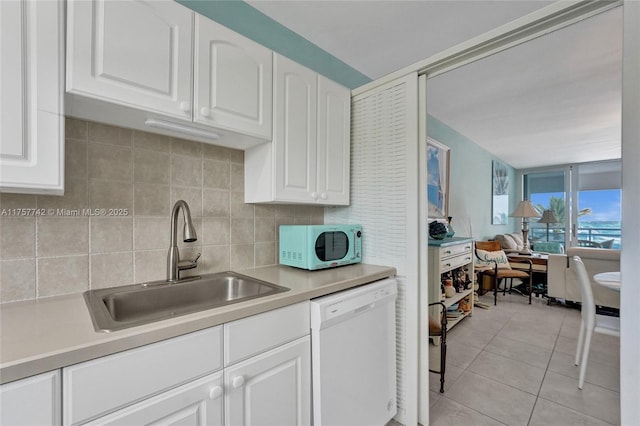 kitchen featuring light countertops, backsplash, light tile patterned flooring, a sink, and white appliances