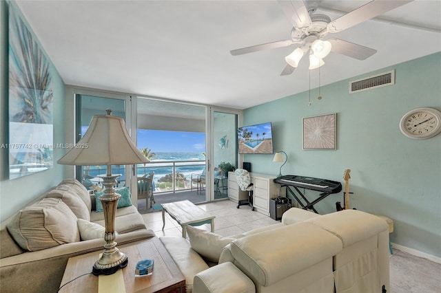 tiled living area featuring a ceiling fan, floor to ceiling windows, visible vents, and baseboards