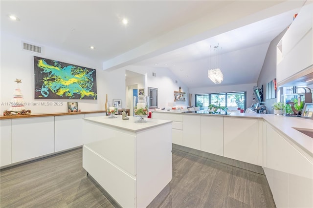 kitchen with visible vents, modern cabinets, wood finished floors, white cabinetry, and vaulted ceiling