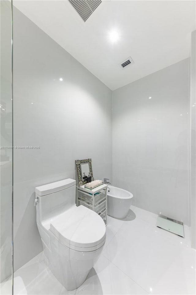 bathroom featuring toilet, a bidet, and visible vents