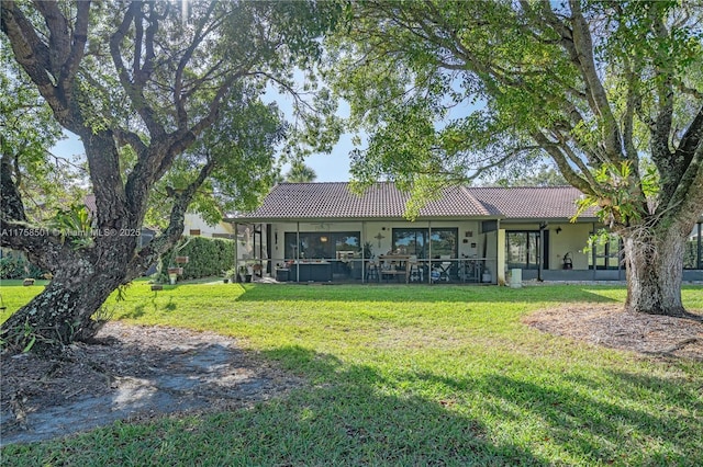 back of property with stucco siding, a lawn, and a tiled roof