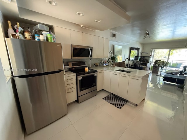 kitchen with visible vents, light countertops, appliances with stainless steel finishes, a sink, and a peninsula