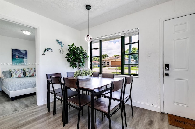 dining area with a textured ceiling, baseboards, and wood finished floors