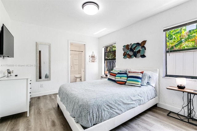 bedroom with multiple windows, baseboards, and wood finished floors