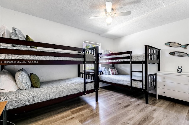 bedroom with a ceiling fan, a textured ceiling, and wood finished floors