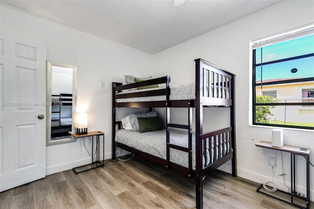 bedroom featuring a textured ceiling, wood finished floors, and baseboards