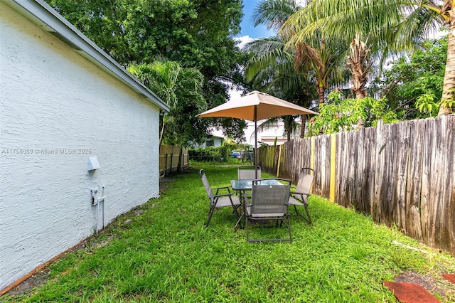 view of yard featuring outdoor dining space and fence