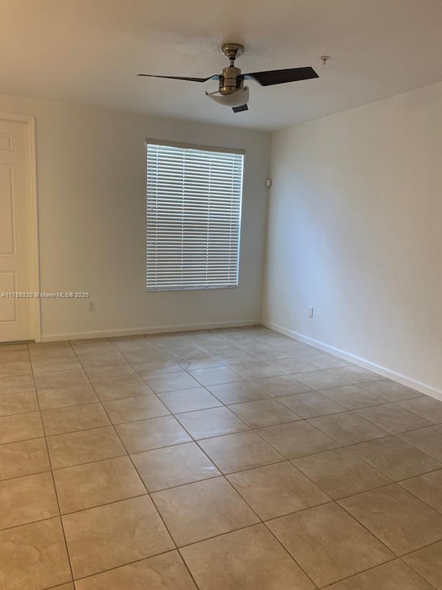 spare room with ceiling fan, light tile patterned flooring, and baseboards