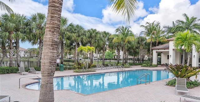 pool with a patio area and fence