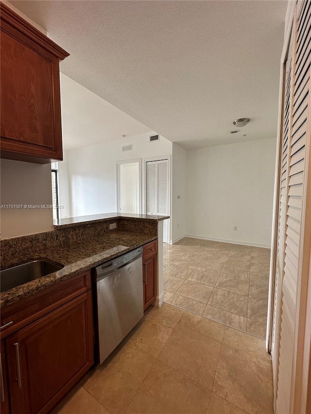 kitchen featuring baseboards, visible vents, dark stone counters, a textured ceiling, and stainless steel dishwasher