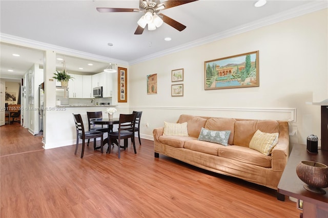 living area with recessed lighting, light wood-style flooring, a ceiling fan, and ornamental molding
