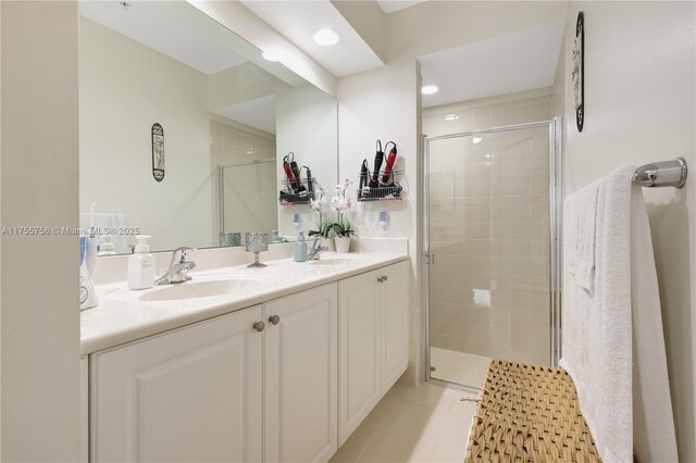 full bath featuring double vanity, a sink, and a shower stall