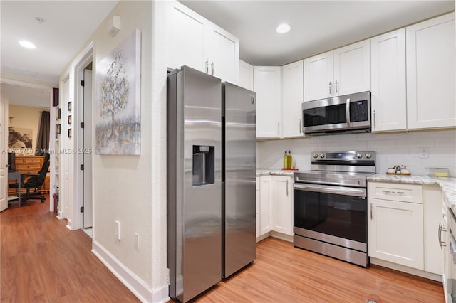 kitchen with appliances with stainless steel finishes, backsplash, white cabinetry, and light wood-style flooring