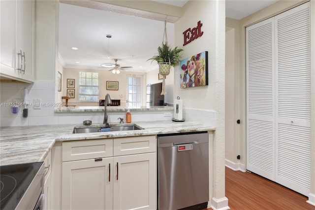 kitchen featuring appliances with stainless steel finishes, ornamental molding, white cabinetry, a sink, and wood finished floors