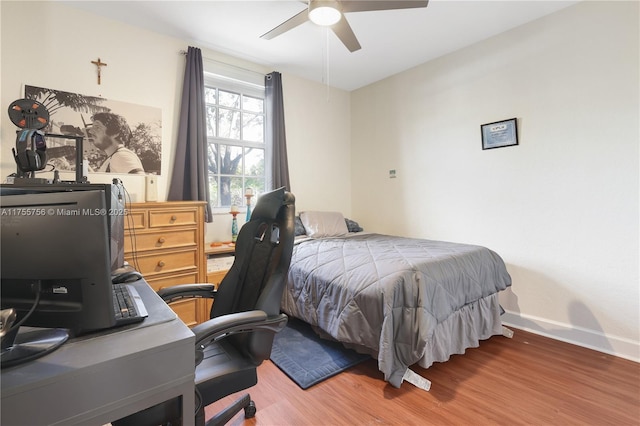 bedroom featuring ceiling fan, baseboards, and wood finished floors