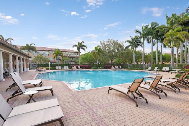 community pool with a patio area and fence