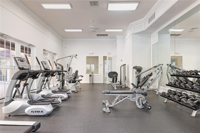 exercise room with ornamental molding, visible vents, and baseboards