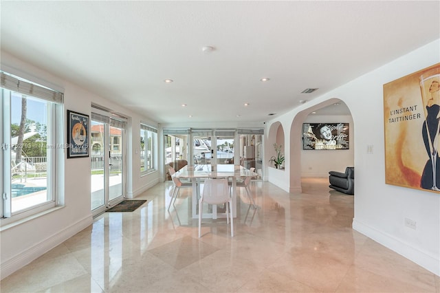 interior space featuring arched walkways, recessed lighting, visible vents, and baseboards