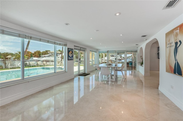 unfurnished dining area featuring arched walkways, recessed lighting, visible vents, and baseboards