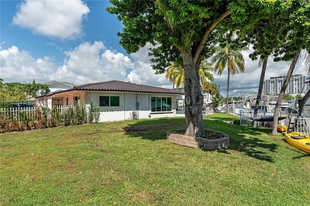 back of property with stucco siding, a lawn, and a tiled roof