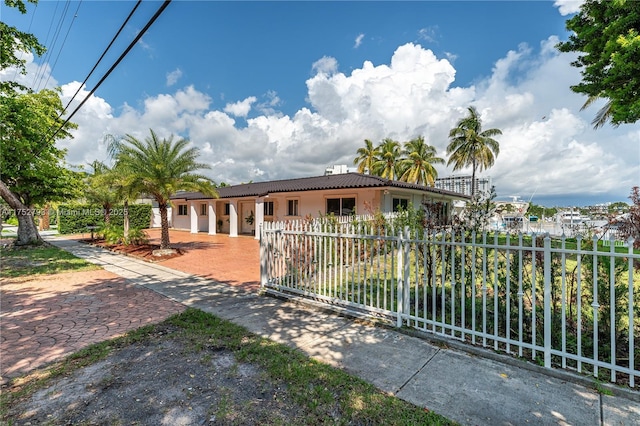 view of front of house with a fenced front yard, a tile roof, and stucco siding