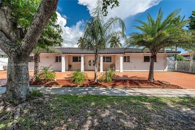 view of front facade with stucco siding, a tiled roof, driveway, and fence