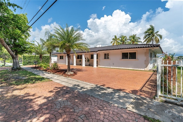 rear view of house with a gate, fence, a tiled roof, and stucco siding