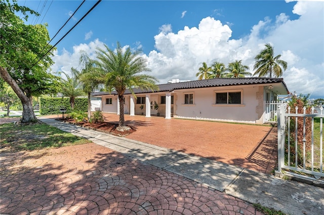 back of property featuring a gate, stucco siding, fence, and a tiled roof