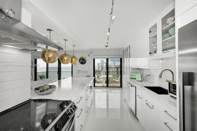 kitchen with tasteful backsplash, appliances with stainless steel finishes, white cabinets, a sink, and wall chimney range hood