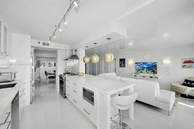 kitchen with stainless steel appliances, open floor plan, wall chimney range hood, and modern cabinets