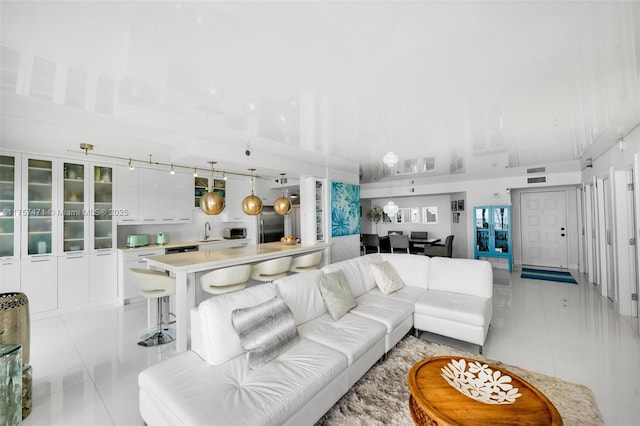 living room featuring light tile patterned floors, a high ceiling, and visible vents