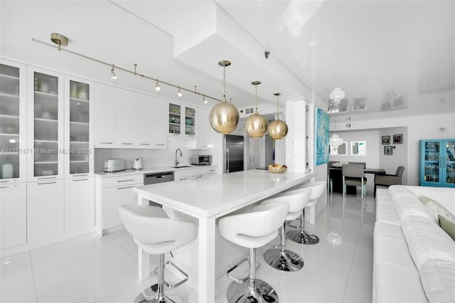 kitchen featuring white cabinets, appliances with stainless steel finishes, a breakfast bar, a sink, and light tile patterned flooring