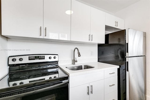 kitchen featuring range with electric cooktop, white cabinets, freestanding refrigerator, light countertops, and a sink