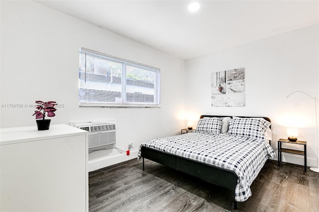 bedroom with baseboards, wood finished floors, and an AC wall unit