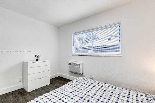 bedroom featuring a wall unit AC, baseboards, and dark wood-type flooring