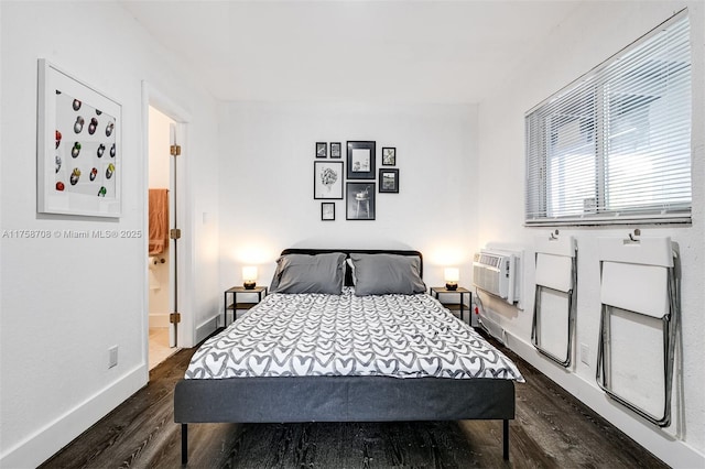 bedroom featuring baseboards, dark wood-style flooring, and an AC wall unit