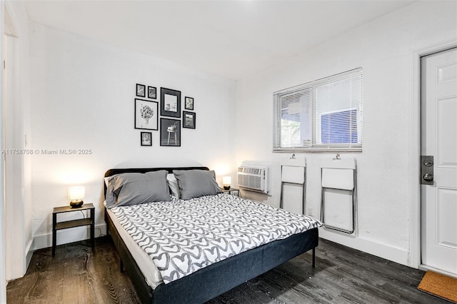 bedroom with dark wood-style floors, baseboards, and a wall mounted AC