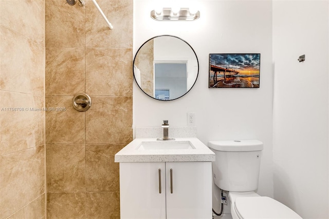 full bath featuring tiled shower, vanity, and toilet