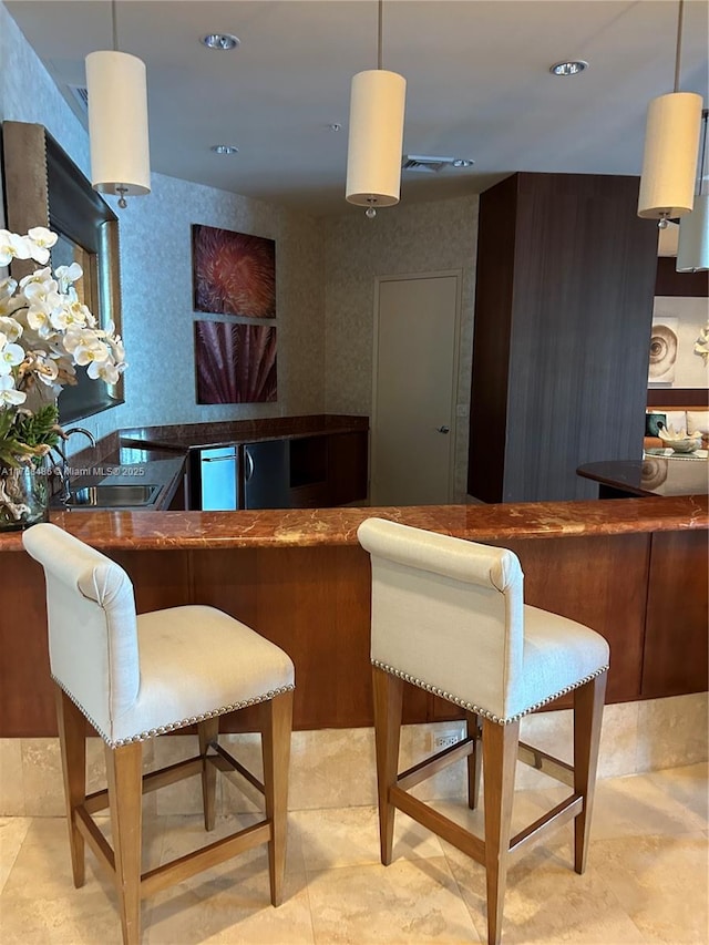 kitchen with wallpapered walls, pendant lighting, a sink, and recessed lighting