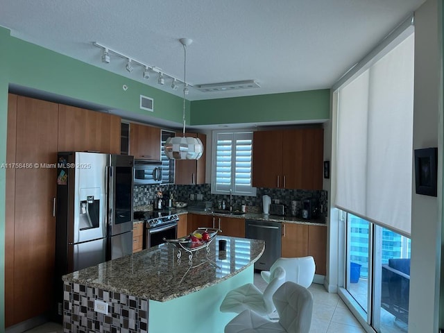 kitchen featuring brown cabinets, tasteful backsplash, visible vents, and stainless steel appliances