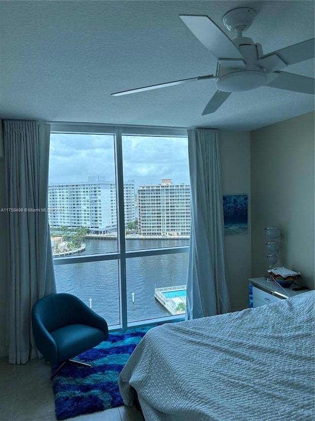 bedroom with floor to ceiling windows, a city view, ceiling fan, a textured ceiling, and tile patterned flooring